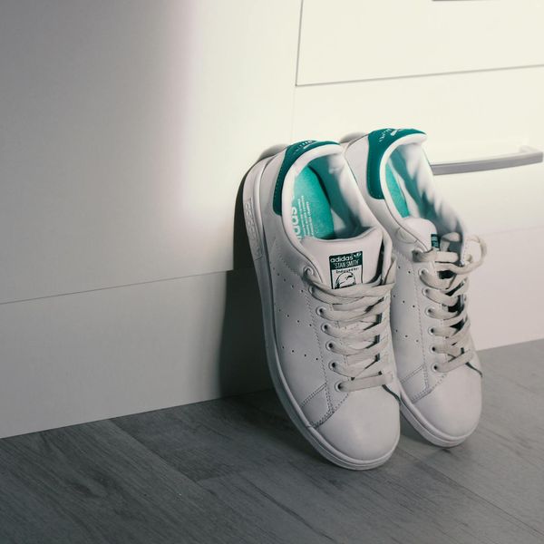 Close-up of athletic shoes on a dark floor with teal light.